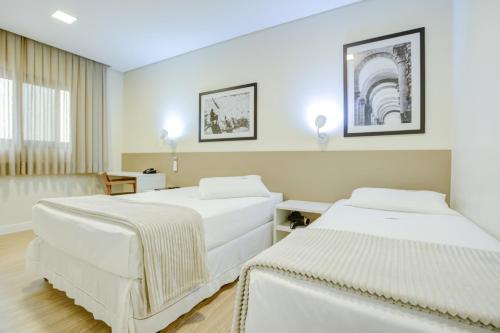 a hotel room with two beds and a window at Hotel Domani in Guarulhos