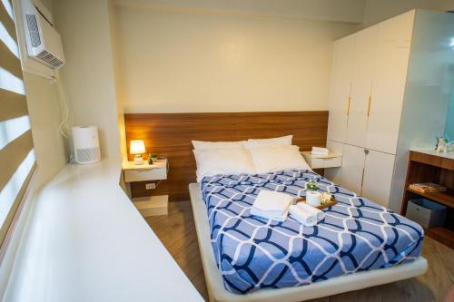 a small room with a bed and two towels at Voice activated studio condo unit at One Regis Megaworld, JK Modern Nest in Bacolod