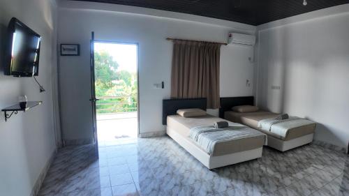 a bedroom with two beds and a television and a window at F&D Homestay in Semporna