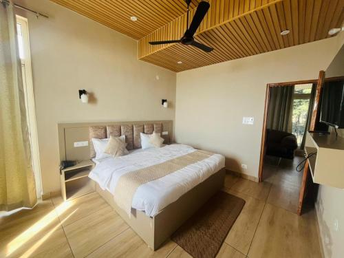 a bedroom with a large bed with a ceiling fan at HOTEL DEVDAR RESORT in Dharmsāla