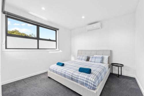 a white bedroom with a bed and a window at Sleek Contemporary Haven Geelong in Highton