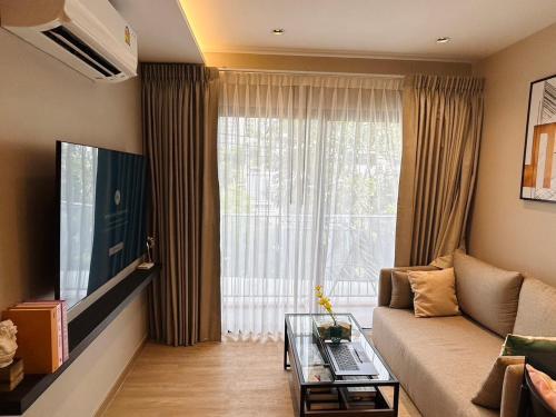 a living room with a couch and a large window at Tierra Residences in Bangkok