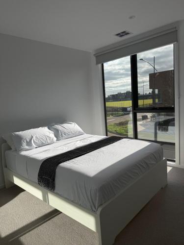 a white bedroom with a bed and a large window at Papillon Home in Rockbank