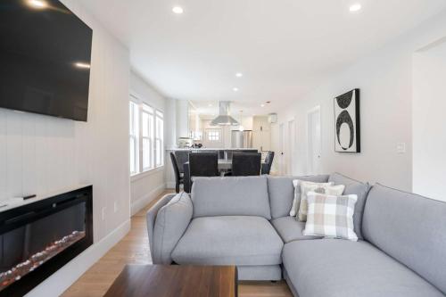 a living room with a gray couch and a tv at Beautiful and Spacious 3BD Condo in Somerville in Somerville