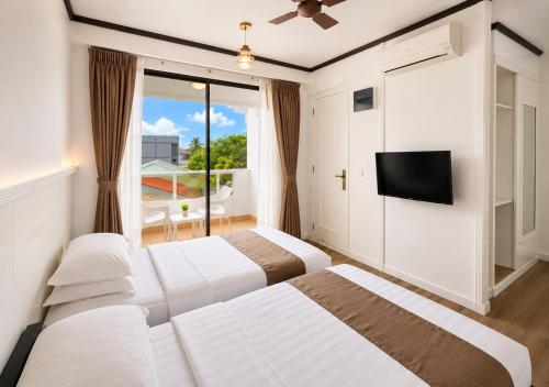 two beds in a hotel room with a tv at Rashu Hiyaa Hotel in Dhiffushi