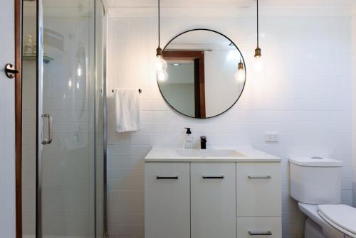 a white bathroom with a sink and a mirror at Garden Cottage, Wellness Studio & Bike Shed in Winnaleah
