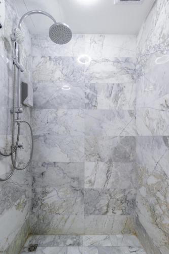 a bathroom with a shower with white marble walls at Beachside 1BR Condo Pool Gym Phuket- MBC C172 in Ban Bo Sai Klang