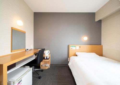 a hotel room with a bed and a desk at Super Hotel Minami Hikone Ekimae in Hikone