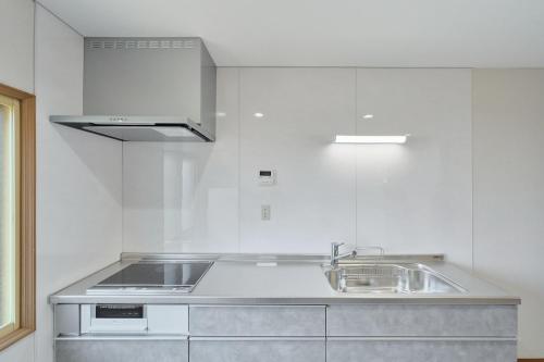 a white kitchen with a sink and a stove at Yunokawa Kagura in Hakodate