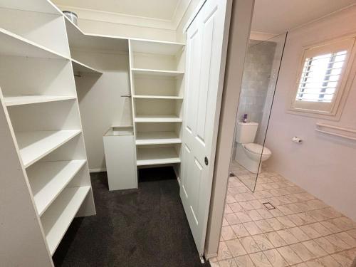 a walk in closet with white shelves and a toilet at Jaspa - River Views - Bring your own linen in South West Rocks