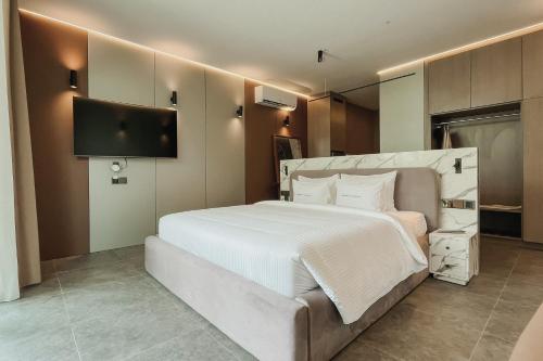 a bedroom with a white bed and a flat screen tv at Awwa Boutique Hotel in Canggu