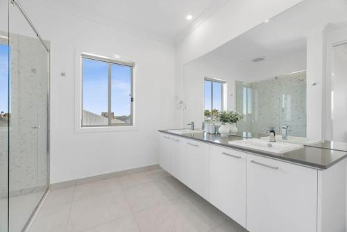 a white bathroom with a sink and a mirror at City & Surf Getaway in Grovedale