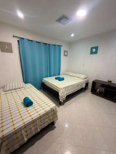 two beds in a room with blue curtains at Habitaciones Casa Lisboa in San Andrés