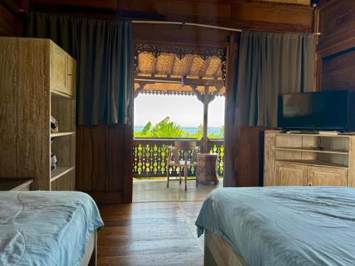 a bedroom with a bed and a television and a balcony at Villa Bakso Mentigi in Teluknarat
