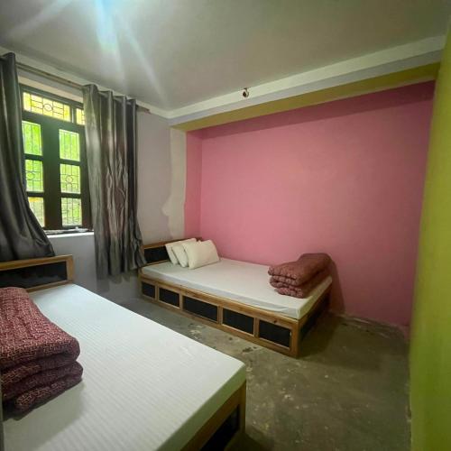 a room with two beds and a pink wall at Briddhim Guest House in Syābru Bensi