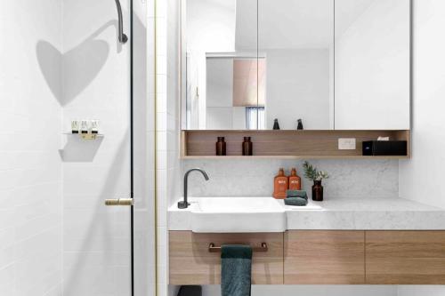 a bathroom with a white sink and a shower at Mod House Ocean Grove- Walk to the shops, cafes, beach and park! Brand new luxury apartment in gated complex in Ocean Grove