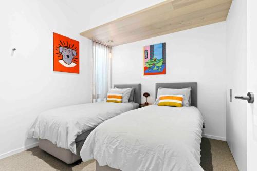 two beds in a bedroom with white walls at Mod House Ocean Grove- Walk to the shops, cafes, beach and park! Brand new luxury apartment in gated complex in Ocean Grove