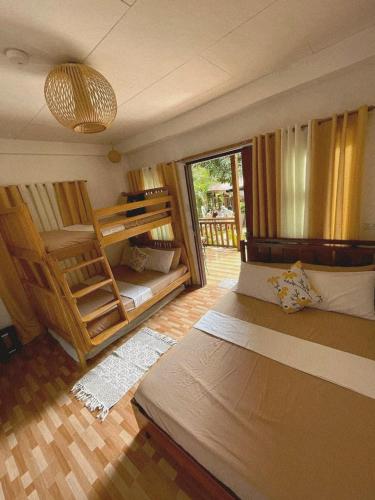 a bedroom with two bunk beds and a balcony at CABIN C at Bigang Munti Beach Resort in Bootin