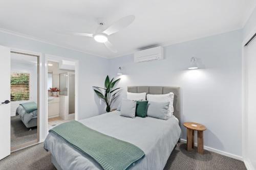 a bedroom with a large bed with a green blanket at Beach Street - Town Location - Stone Real Estate Yamba in Yamba