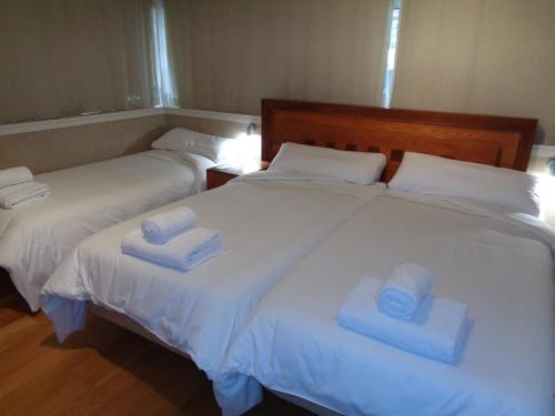 two beds with white sheets and blue towels on them at Hotel Villa De Betanzos in Betanzos