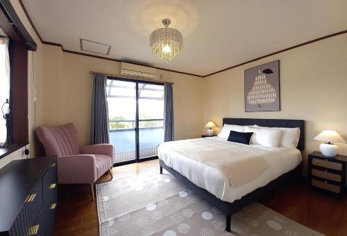 a bedroom with a bed and a chair and a window at Villa Nami in Kashima