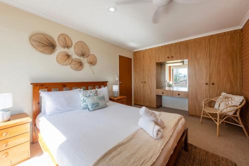 a bedroom with a large bed and a chair at Elsewhere 3- Town Location - Stone Real Estate Yamba in Yamba