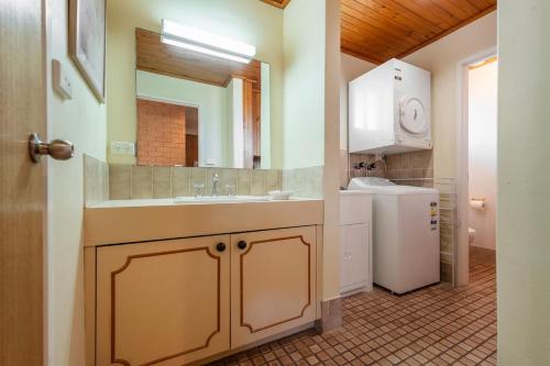 a bathroom with a sink and a washer and dryer at Elsewhere 3- Town Location - Stone Real Estate Yamba in Yamba