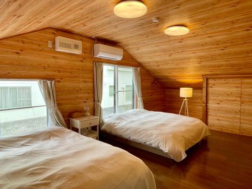 a bedroom with two beds in a room with wooden walls at Asu base Yuge in Hachimantai