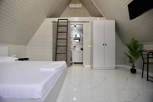 a bedroom with a large white bed and a ladder at VLD House A Frame in Vadu