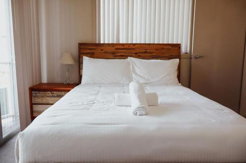 a large white bed with two towels on it at Seaspray 8 - Ocean Views - Stone Real Estate Yamba in Yamba