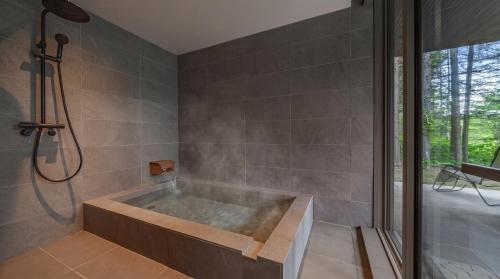 eine Badewanne in einem Badezimmer mit Dusche in der Unterkunft Noah Rusutsu in Rusutsu
