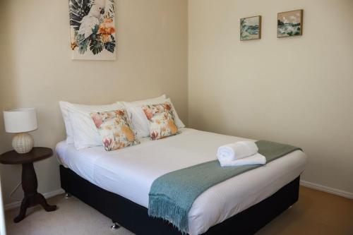 a small bedroom with a bed with white sheets and pillows at Oceania Cottage- Pet Friendly -Stone Real Estate Yamba in Yamba
