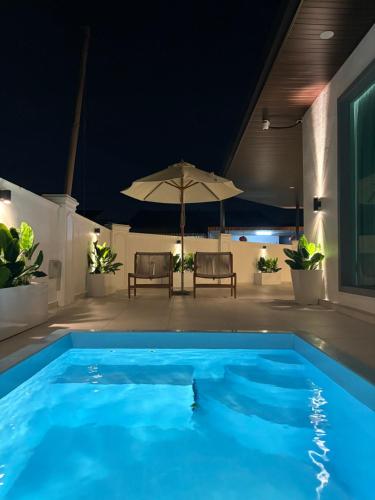 a large blue swimming pool with an umbrella at Chin Villa in Simpang Ampat
