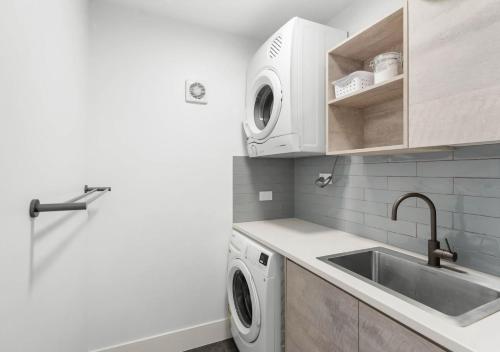 a kitchen with a sink and a washing machine at Pippi Sands - Pet Friendly - Stone Real Estate in Yamba