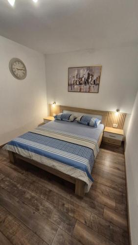 a large bed in a bedroom with a clock on the wall at APARTMANI PAVLOVIC in Zelenika