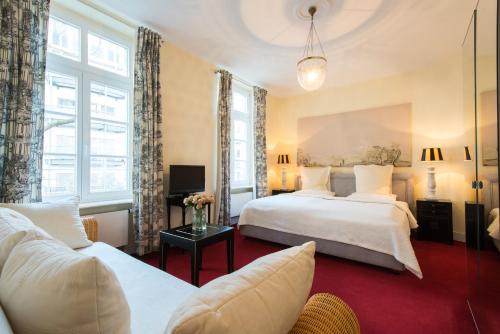 a hotel room with two beds and a couch at DIRAZI Guesthouse & Apartments GmbH in Frankfurt
