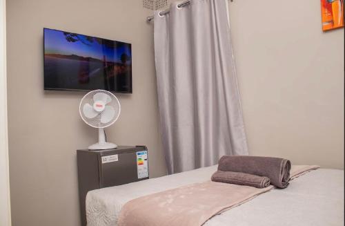 a bedroom with a bed with a fan and a window at MbaliBliss in Bulawayo