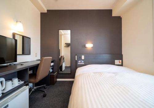 a hotel room with a bed and a desk and a television at Super Hotel Asahikawa in Asahikawa