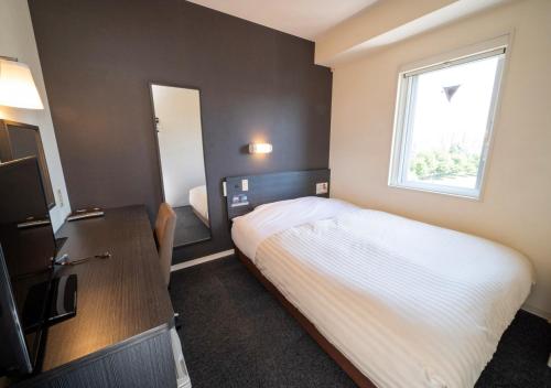a small bedroom with a bed and a window at Super Hotel Asahikawa in Asahikawa