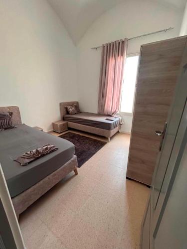 a bedroom with a bed and a chair and a window at djerba palm house in Mezraya