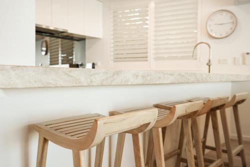 a kitchen with a counter with three stools at a bar at Noosa Harbour Resort in Noosa Heads