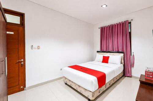 a bedroom with a bed with a red blanket at RedDoorz at Residence Bintaro in Mencil