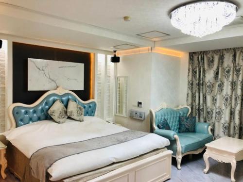 ein Schlafzimmer mit einem großen Bett und einem blauen Stuhl in der Unterkunft ロコズリゾートハワイandオアフ in Honjo