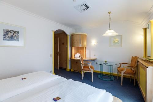 a bedroom with a bed and a table and chairs at Das-Schmidt Privathotel in Mörbisch am See