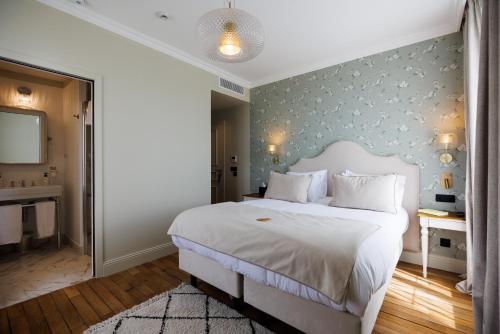 a bedroom with a large white bed and a television at Villa Edmond Hôtel & Spa - Maison Blanche Bièvres in Bièvres