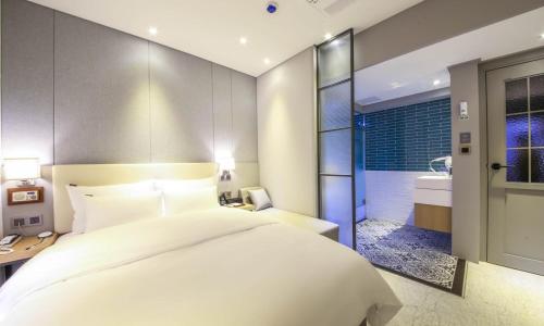 a bedroom with a large white bed and a bathroom at Brooks Hotel Tongyeong in Tongyeong