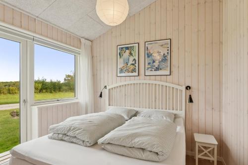 a bedroom with a bed with white pillows and a window at Spacious Holiday Home On Bogø in Bogø By