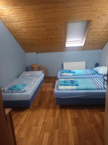 two beds in a room with a wooden ceiling at Čarodějnický Dvůr in Biskoupky