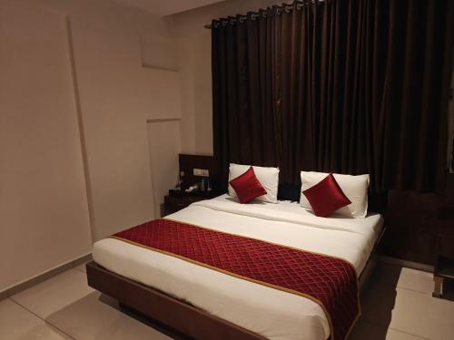 a bedroom with a large bed with red pillows at Hotel Vivank in Kolhapur