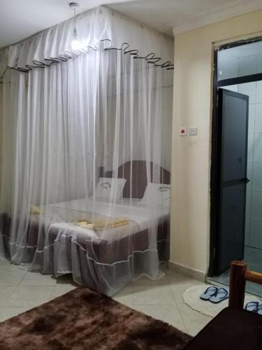 ein Schlafzimmer mit einem Bett und einem weißen Vorhang in der Unterkunft Luanda Road View Hotel in Luanda